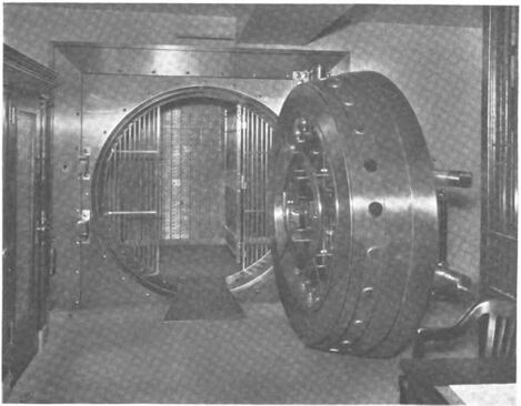 Vault with door open revealing a steel grill and safe deposit boxes
