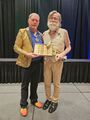 James Ozanich passing the Golden Boot Award to Jim Babcock, 2024